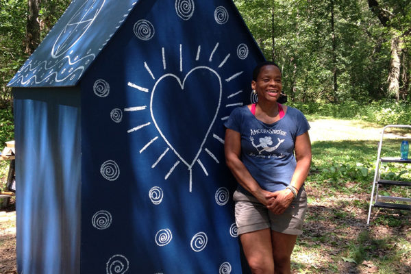 Local artist Ife Franklin posing with her completed installation titled "Slave Cabin" in Franklin Park.